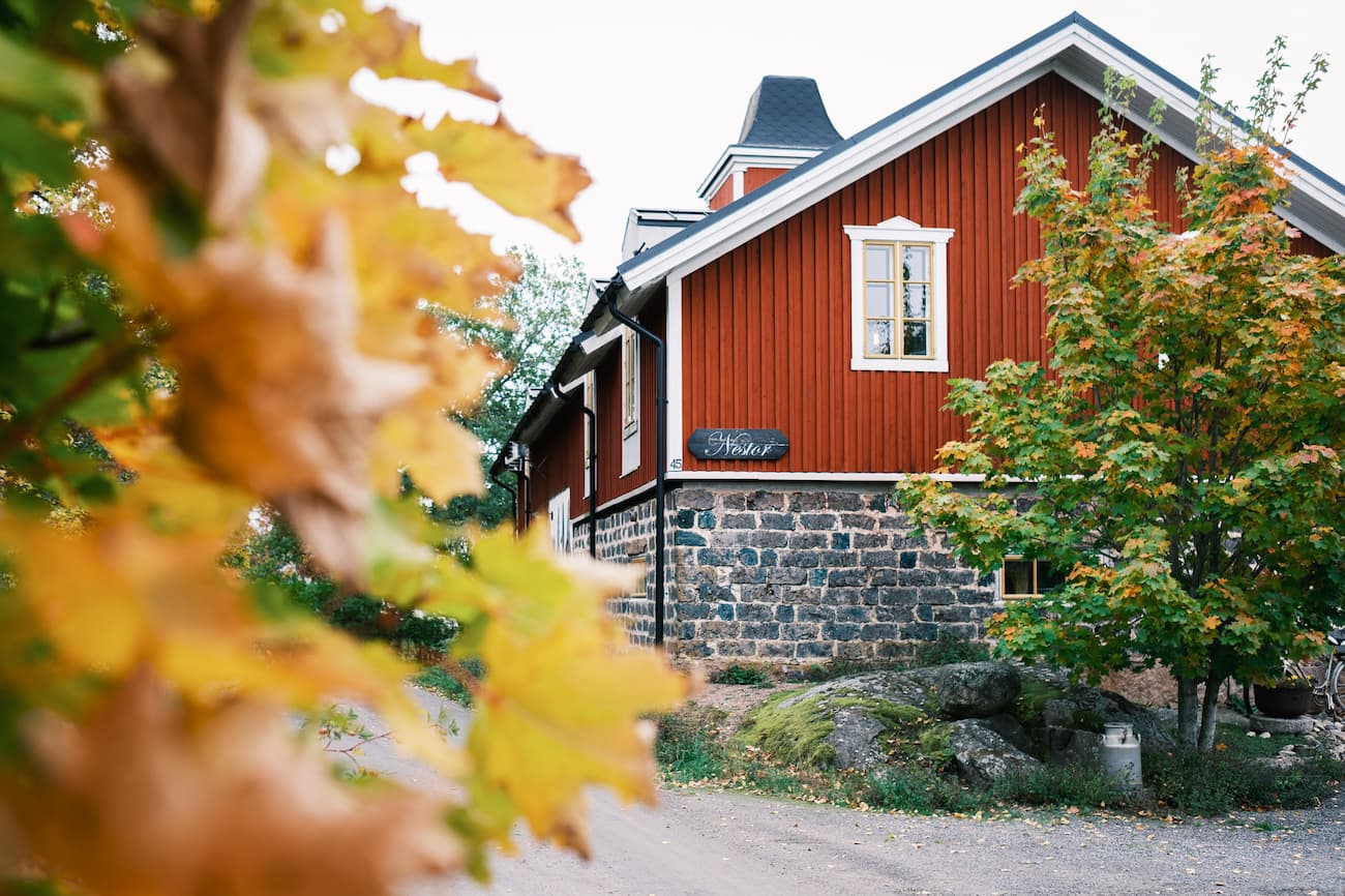 Hotel Nestor med stenfundament och en skylt med texten &rdquo;Nestor&rdquo;, omgiven av h&ouml;stl&ouml;v.